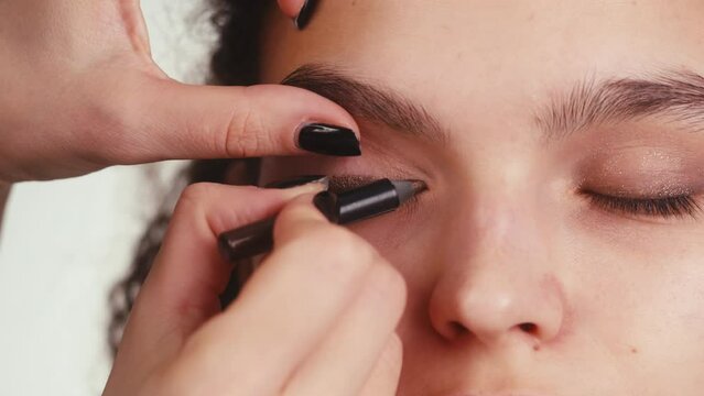 Eye shadow makeup to the upper eyelid, close-up. Makeup artist applies a bright eye shadow with a make-up brush.Tutorial master class of professional makeup, smoky eyes 