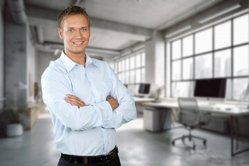 Happy businessman standing at workplace in office