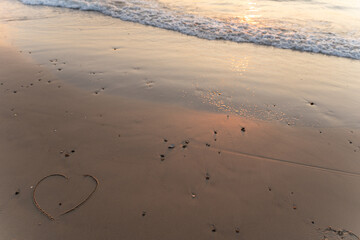 Hearth symbol on sand against a background of sunset over the sea