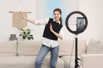 Smiling teenage blogger dancing while streaming at home