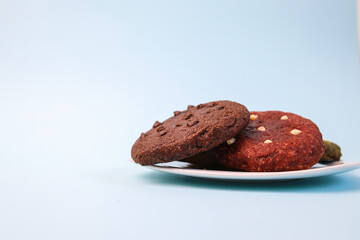Various Cookies Topped With Choco Chips On White Plate Isolated On Blue Background