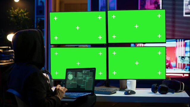 Man writing code on laptop in front of isolated screen PC monitors, trying to get past security systems. Hacker using chroma key computer and notebook to make scripts that can hack devices, camera A