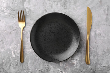 Elegant setting with golden cutlery on grey textured table, flat lay