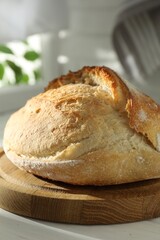 Freshly baked sourdough bread on white wooden table indoors