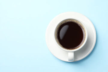 Cup of aromatic coffee on light blue background, top view. Space for text