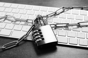 Cyber security. Metal combination padlock with chain and keyboard on grey table, closeup