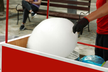 Man making cotton candy with machine outdoors, closeup