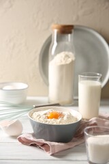 Making dough. Flour with yolk in bowl on white wooden table