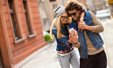 Couple taking selfie in the street wearing casual clothes