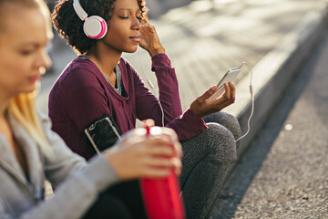 Young African American woman listening to music while sitting outdoors