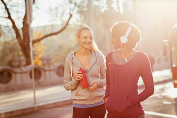 Two women jogging together outside with headphones
