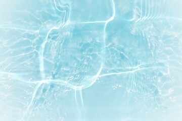Blue water with ripples on the surface. Defocus blurred transparent blue colored clear calm water surface texture with splashes and bubbles. Water waves with shining pattern texture background