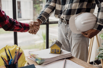 Architect and construction engineer holding hands while working for teamwork and cooperation concept after completing an agreement at construction site, office, close-up image