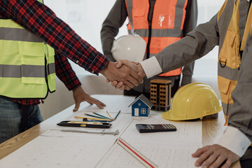 Architect and construction engineer holding hands while working for teamwork and cooperation...