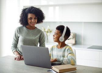 A young mother helps her son with his homework. The boy looks at the laptop.