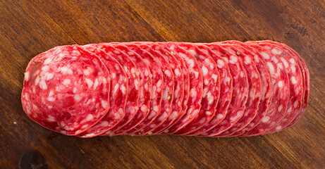 Top view of smoked salchichon sausage slices on wooden background
