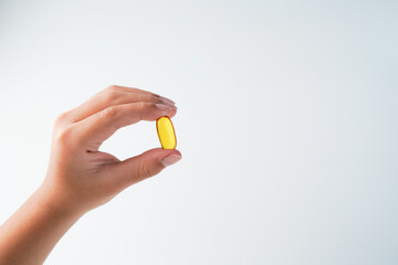 fingers holding a oil filled capsule, soft gel, food supplements, fish oil, omega 3 omega 9