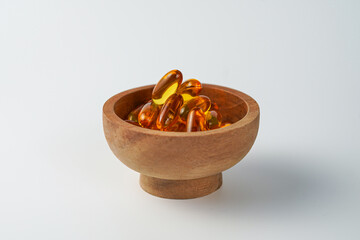 oil filled capsule, soft gel, Fish oil supplement capsule in wooden bowl, omega 3, vitamin D