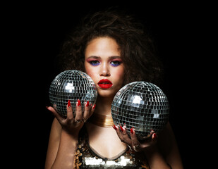 Portrait of young beautiful african woman with bright make up holding disco ball over black...