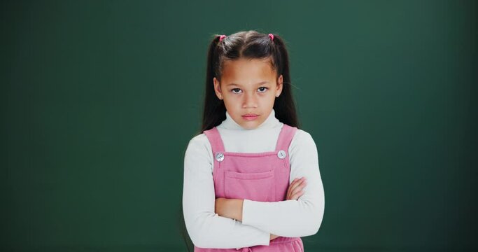 Angry, face and girl with arms crossed in studio with grumpy attitude, tantrum or conflict. Frustrated, kid and emoji of upset child with anger and negative mood in dark background or fashion mockup
