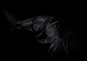 Naklejka premium Black velvet felt fabric flying in curve shape, Piece of textile black velvet felt fabric throw fall in air. Black background isolated, dark shading environment