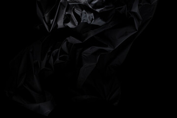 Black wrinkle mussed fabric flying in curve shape, Piece of textile Black wrinkle mussed fabric throw fall in air. Black background isolated, dark shading environment