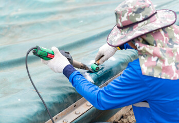 Hot-wedge blower patching plastic canvas and roller compress.