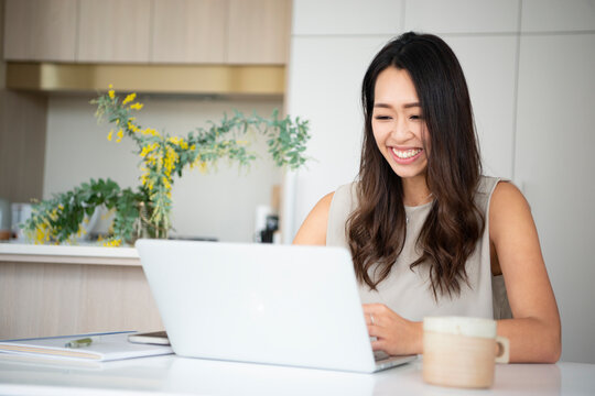 家でパソコンを開いて作業をしている女性