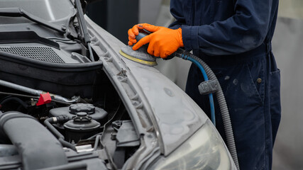 A mechanic sands the putty on a car body with a machine. Repair after an accident. 