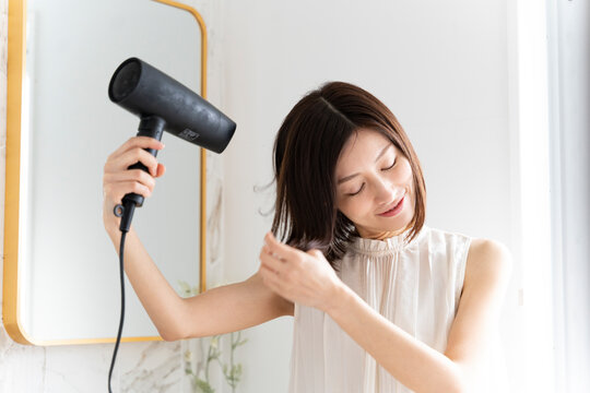 髪にドライヤーをかけている女性