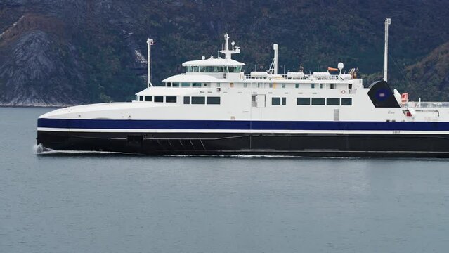 Passenger ferry crosses the fjord. Heavy clouds in the sky.