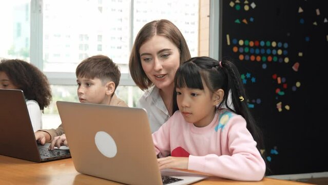 Smart teacher teaching and looking student using laptop at classroom. Professional instructor explained about programing engineering code or prompt while studying and learning program. Erudition.