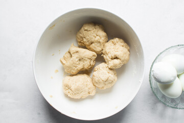 overhead view of dough for making nigerian egg roll in a white ceramic bowl, process of making nigerian egg roll and small chops