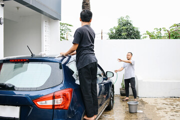 Father Telling Son To Wipe The Car Rooftop. Son Helping Father To Washing Car