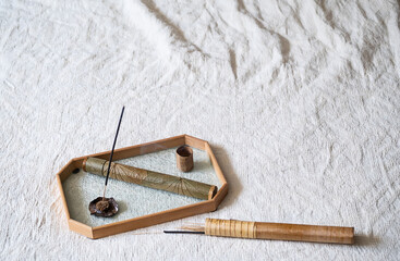 Stick of incense burning on glass tray.