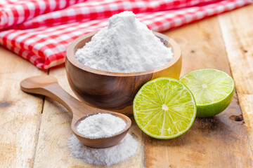 Baking soda in wooden bowl and lemons, on the table