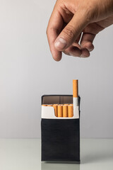 Hispanic hand removing cigarette from black package
