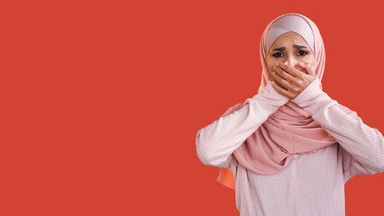 Shocked face. Fear anxiety. Embarrassment shame. Disturbed terrified woman in hijab covering mouth...