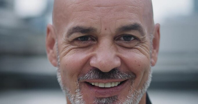 Close-up attractive bald man with goatee smiling with open and friendly smile. Warm smile radiates positive energy and puts ease. Disarming smile charismatic man creates atmosphere trust and comfort.