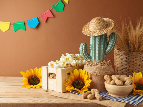 Festa Junina party background with popcorn, peanuts and cactus decoration on wooden table. Brazilian summer harvest festival concept.