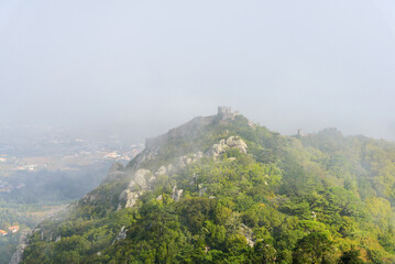 aerial view from the Pena Palace of the Arab castle in the mysterious fog, foggy landscape. Sintra,...