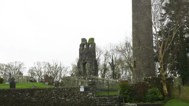 Preserved 9th Century Church Round Tower In Donaghmore Cemetery, Navan, County Meath, Ireland. Tilt-up Shot