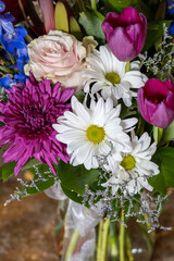 Close up texture background of an indoor florist’s bouquet arrangement containing colorful flowers, with defocused background