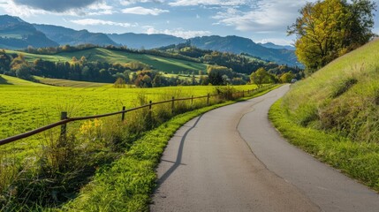 Obraz premium A road runs through a grassy field with a fence on the side