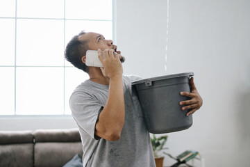 Water leaking from ceiling into buckets in living room as a man calling for insurance company 