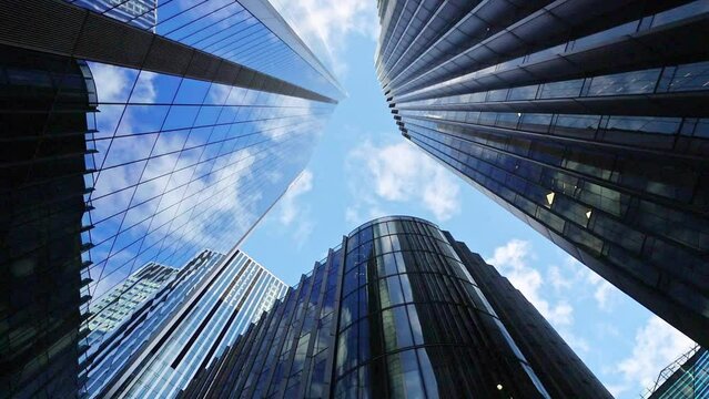 Time-lapse of skyscraper buildings in business district, London City. Cloud on sunny day sky. Low angle view. Europe financial economy, merger and acquisition, or modern architecture concept