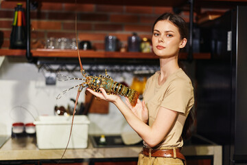 Woman holding lobster in kitchen with stove and refrigerator in background
