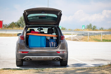 Open car trunk, suitcases and bags in trunk of car ready to depart for holidays