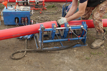 Carrying out butt welding of polyethylene pipes in the field. A worker installs pipes into a welding machine.