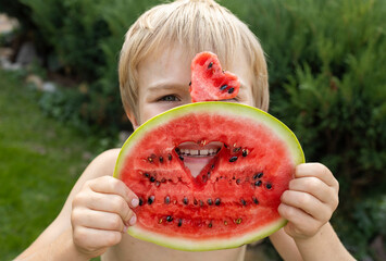 child cheerfully eats watermelon. the boy's face is hidden behind a piece of watermelon and a heart...